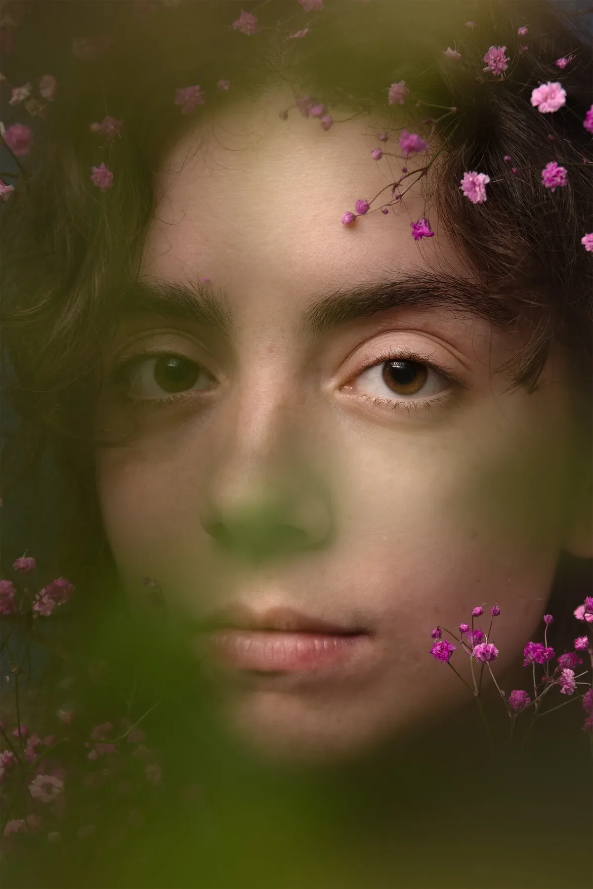 Incanto: il volto di Sole tra fiori viola e vegetazione