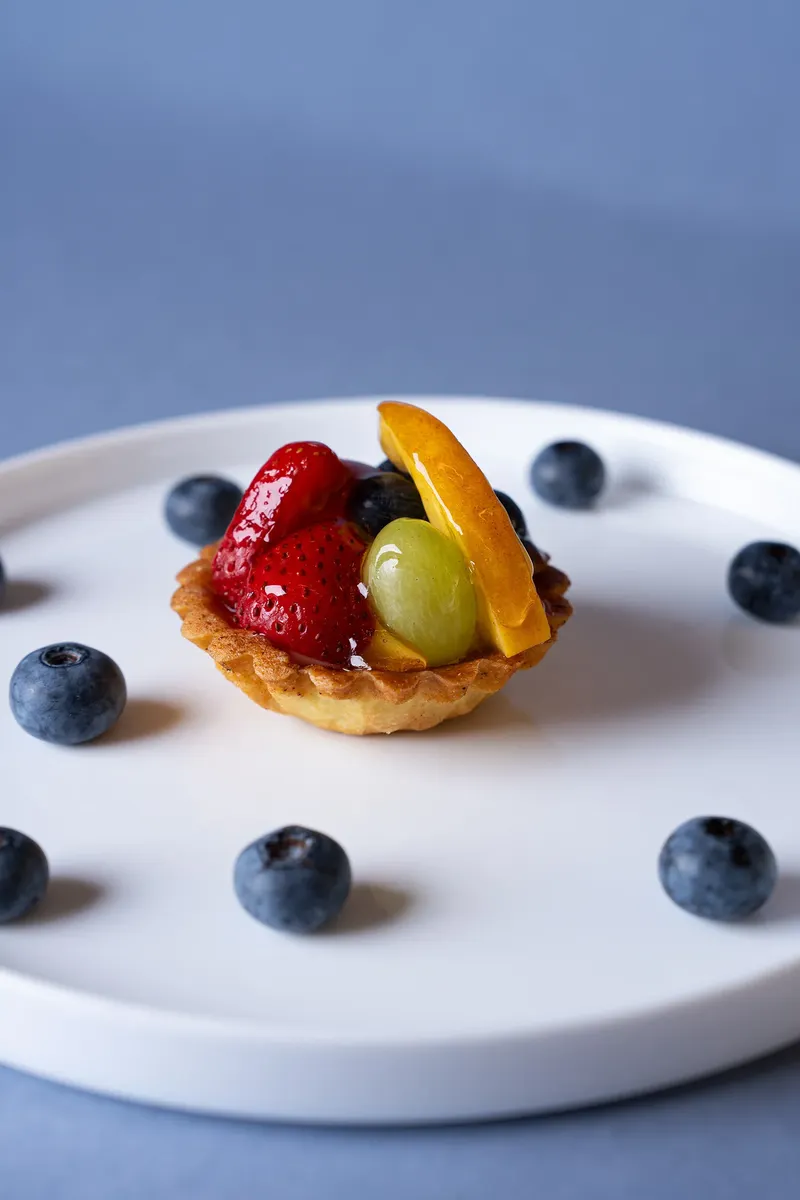 Crostatina alla frutta vista dall’alto tra i mirtilli