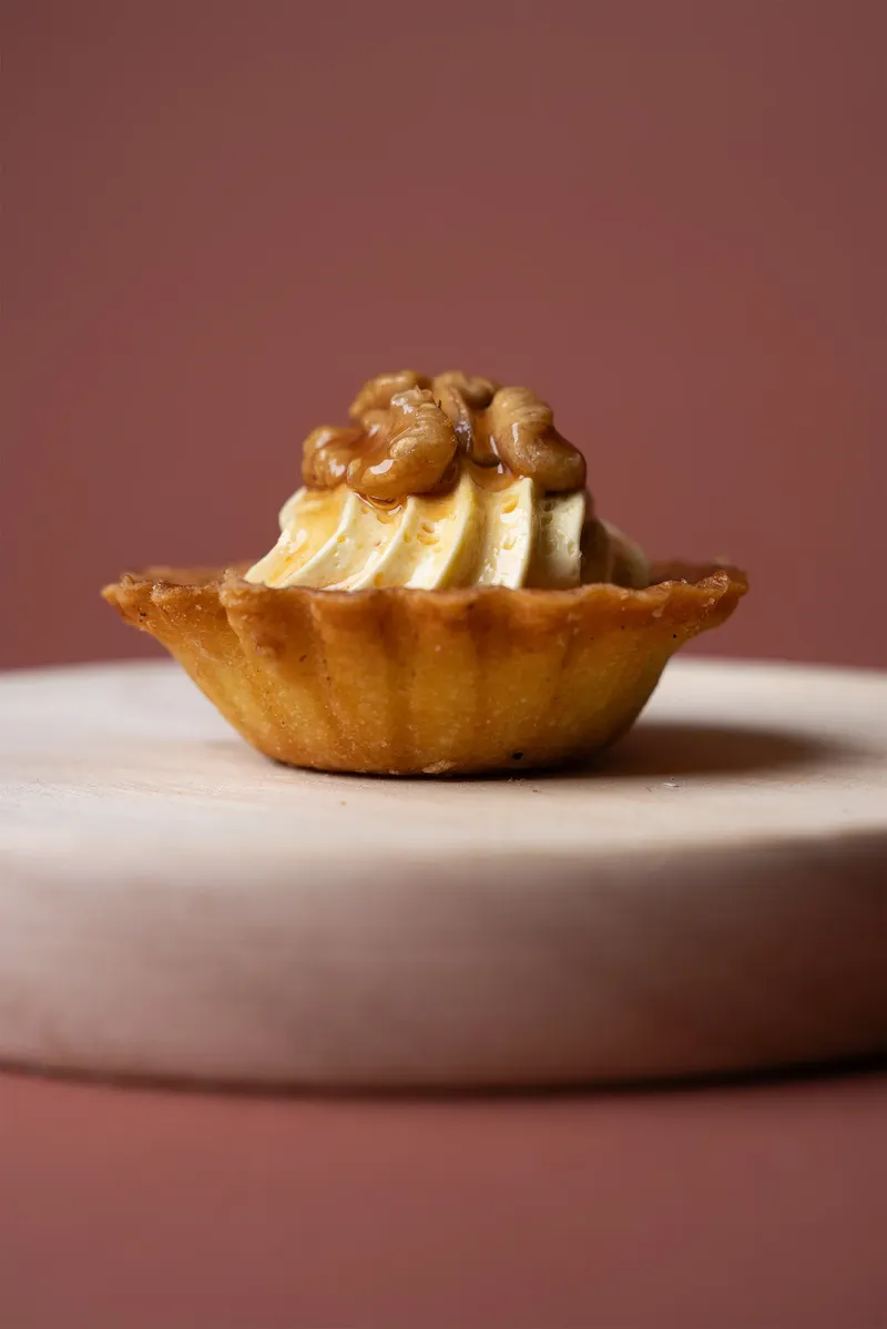 Pasticcino alle noci su tagliere di legno, fondale rosa
