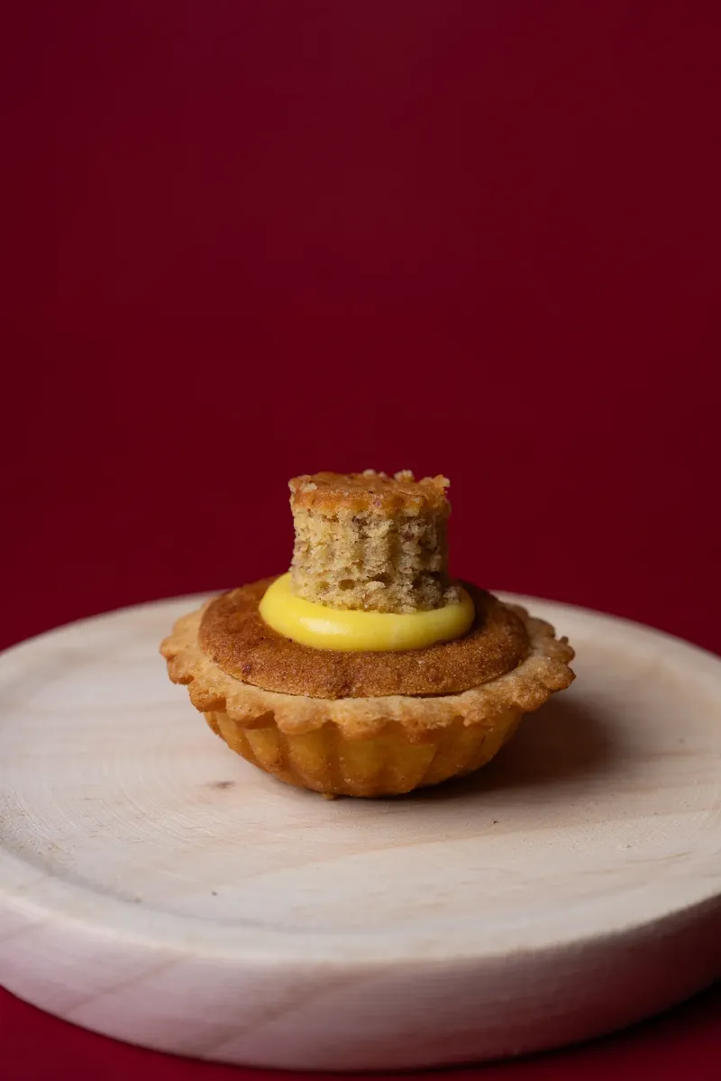 Tortina con crema gialla su tagliere di legno, fondale bordeaux