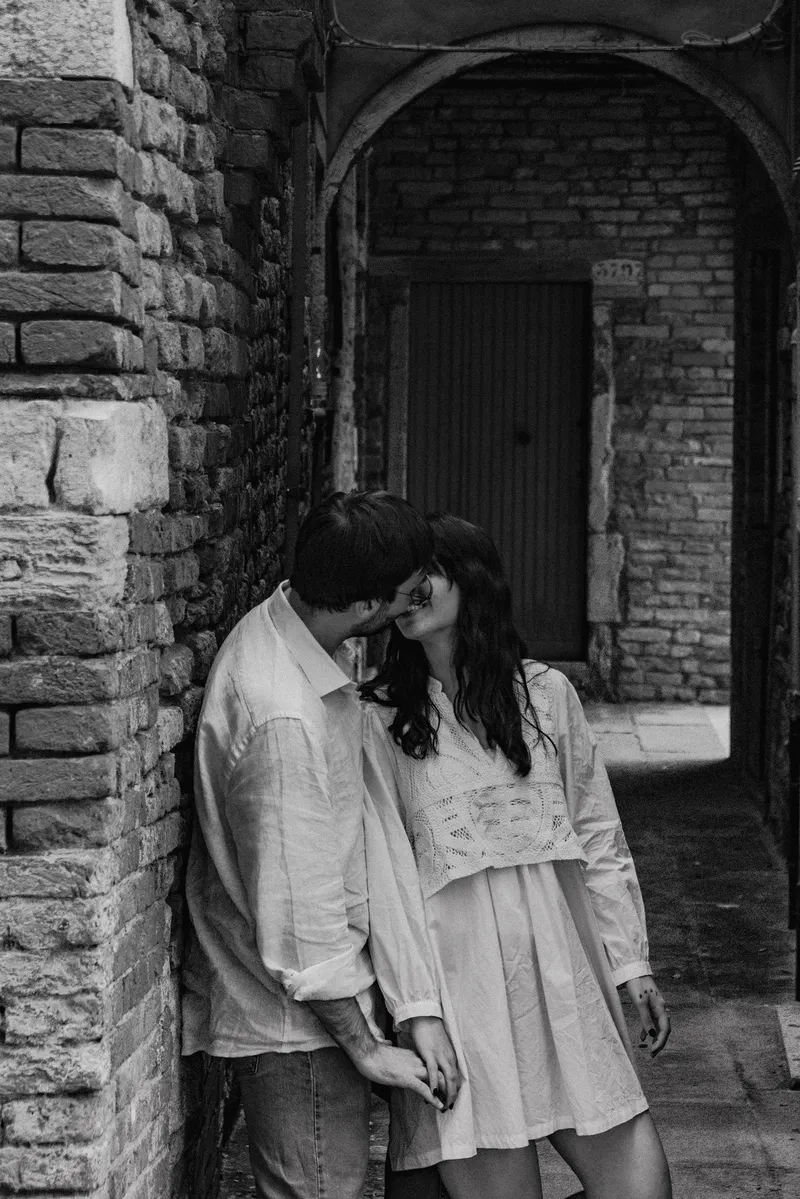 Veronica e Davide abbracciati sotto un arco di mattoni in una calle veneziana
