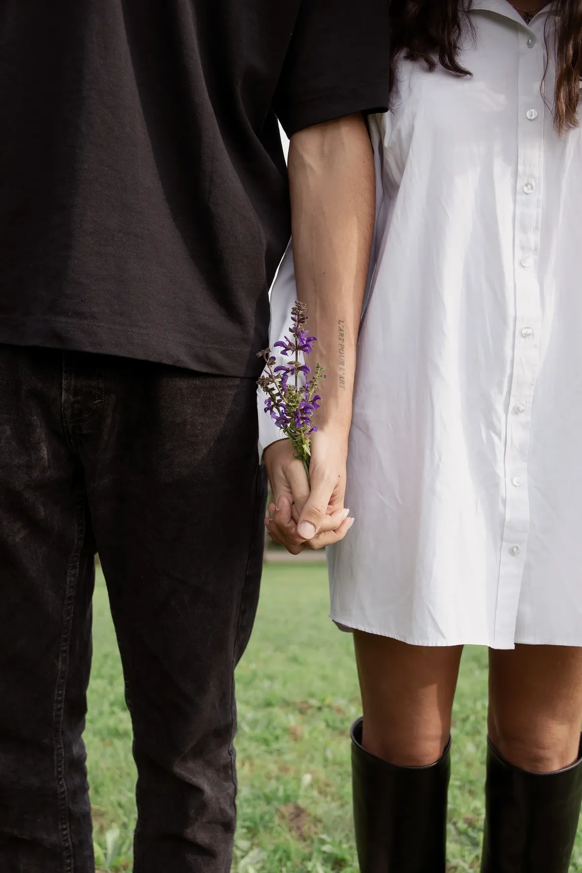 Ilaria ed Edoardo mano nella mano sul prato, lei tiene un rametto di fiori