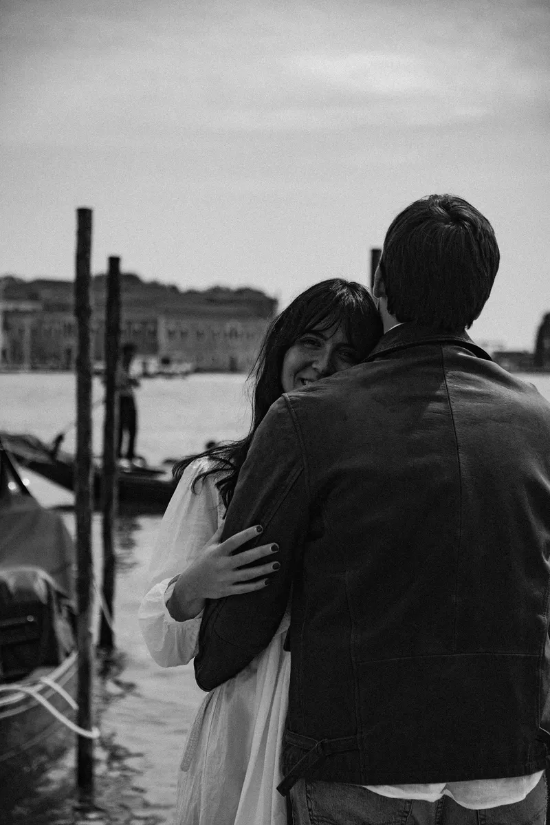 Veronica e Davide abbracciati sulla riva, guardano la laguna