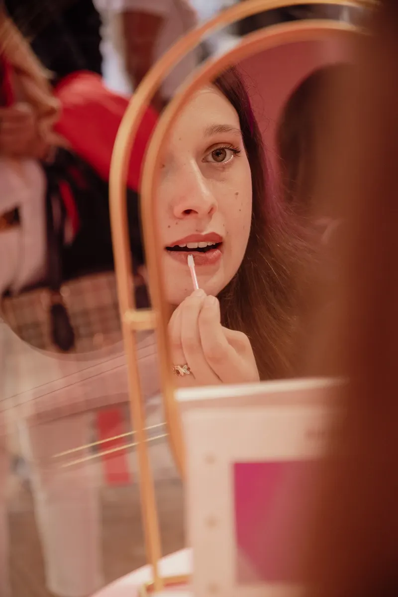 Una ragazza si prova il gloss allo specchio