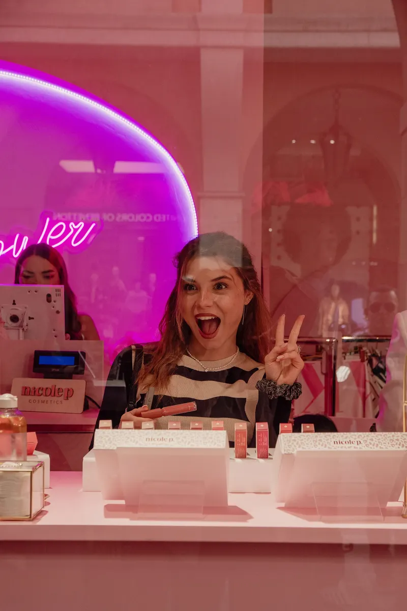 Ragazza sorridente dietro il bancone sotto l’insegna al neon